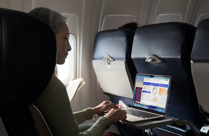 En person sidder i et flysæde og arbejder på en MacBook Air