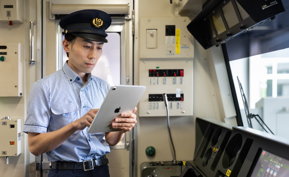 Un conducteur se sert d’un iPad alors qu’il se trouve debout dans la cabine lumineuse du train.