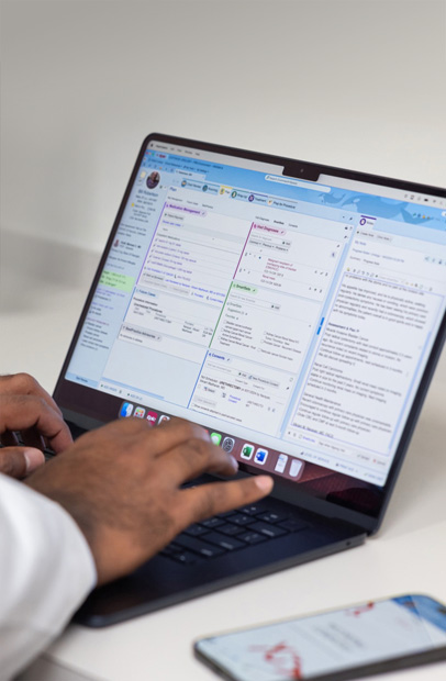 En behandler som sjekker elektroniske pasientjournaler på en MacBook Pro.