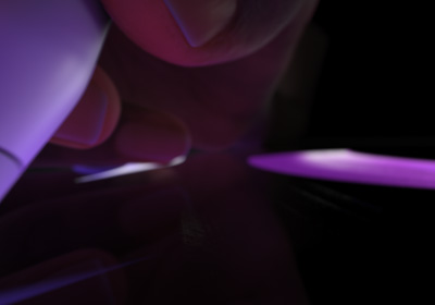 Una mano sujeta el Apple Pencil Pro en posición de escribir. La punta presiona una pantalla y muestra cómo se dibujan trazos de color morado fosforito.