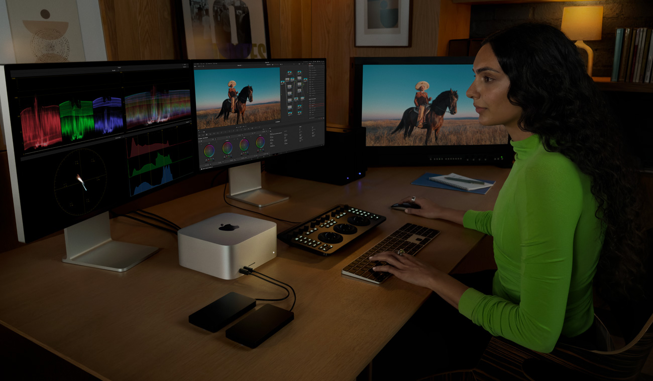 Una persona usa el Mac Studio para editar archivos con tres monitores